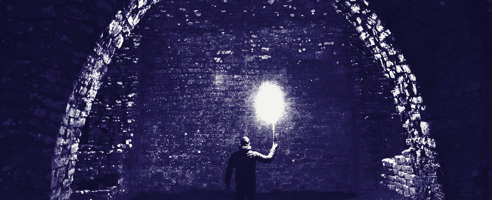 A torch carried under a stone arch at night
